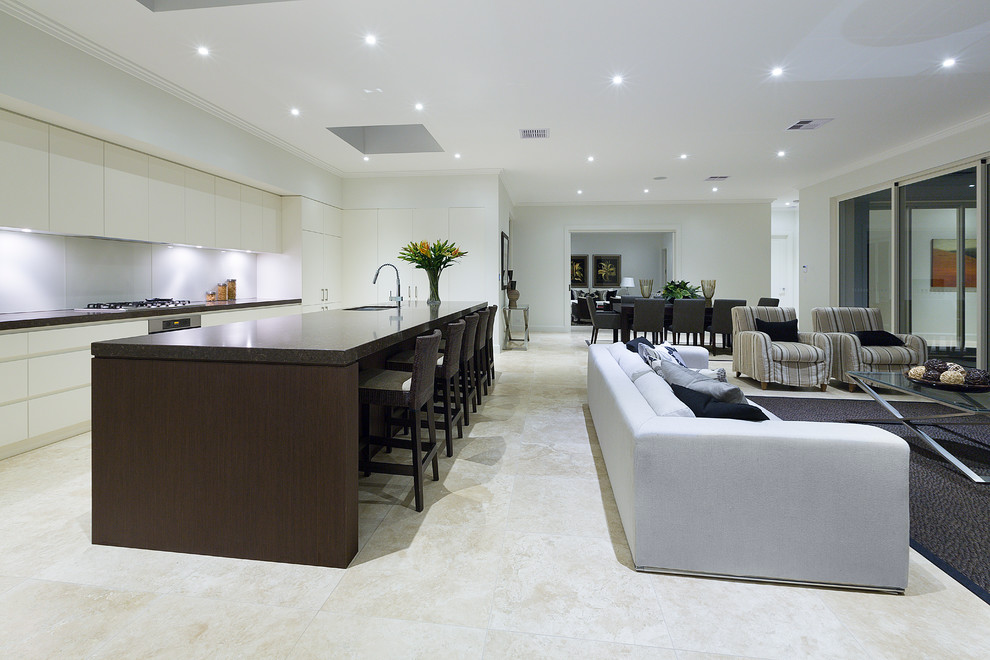 Photo of a transitional l-shaped open plan kitchen in Sydney with an undermount sink, flat-panel cabinets, white cabinets, quartz benchtops, white splashback, glass sheet splashback, stainless steel appliances, limestone floors and with island.
