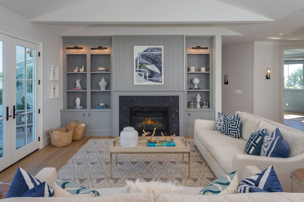 This is an example of a large beach style formal open concept living room in Los Angeles with grey walls, medium hardwood floors, a standard fireplace, a tile fireplace surround, brown floor and no tv.