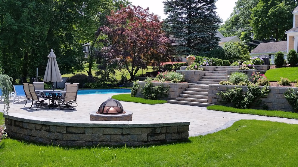 Design ideas for a large traditional backyard custom-shaped lap pool in New York with natural stone pavers.