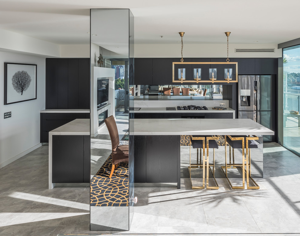 Mid-sized modern galley eat-in kitchen in Sydney with an undermount sink, black cabinets, quartz benchtops, mirror splashback, stainless steel appliances, porcelain floors, with island, white floor and white benchtop.