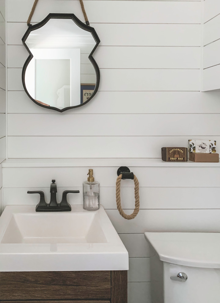 Maritim inredning av ett litet vit vitt badrum, med släta luckor, skåp i mellenmörkt trä, vit kakel, cementgolv, bänkskiva i kvartsit och svart golv