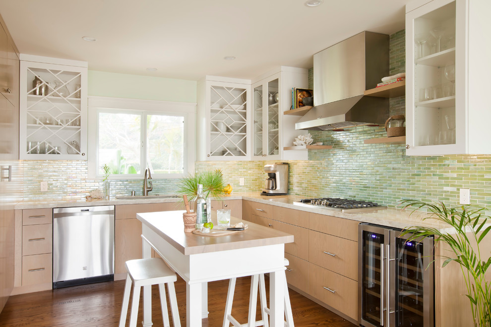 This is an example of a mid-sized beach style u-shaped kitchen in Los Angeles with an undermount sink, glass-front cabinets, white cabinets, green splashback, subway tile splashback, stainless steel appliances and medium hardwood floors.