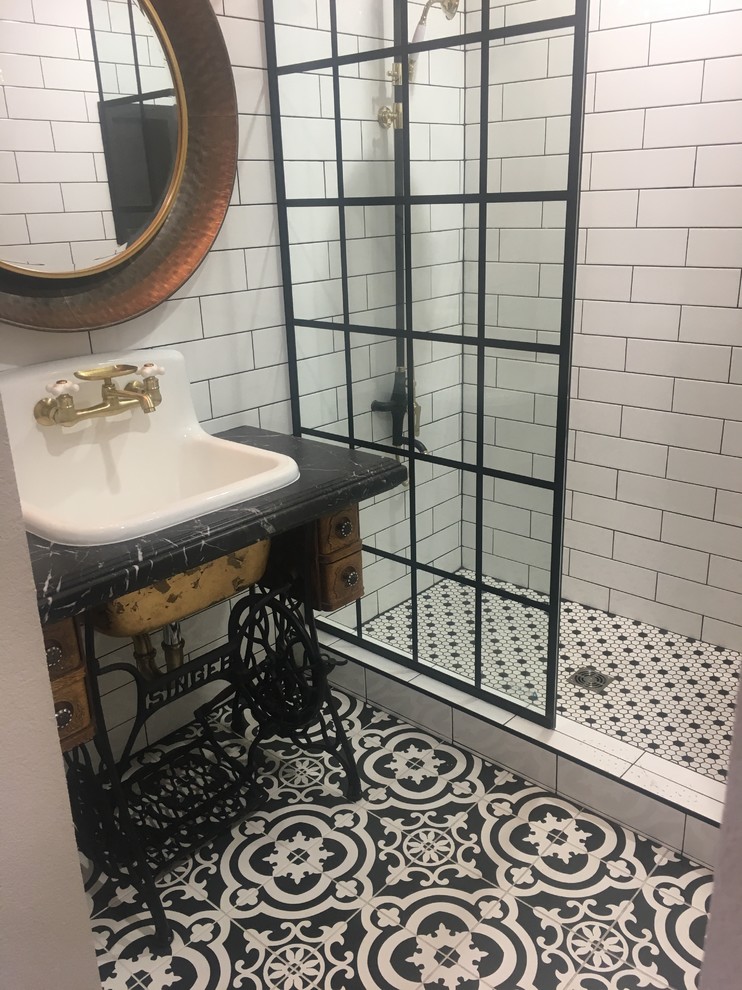 Inspiration for a mid-sized industrial 3/4 bathroom in Las Vegas with furniture-like cabinets, brown cabinets, an open shower, a wall-mount toilet, black and white tile, subway tile, white walls, porcelain floors, a drop-in sink, granite benchtops, white floor, an open shower and black benchtops.