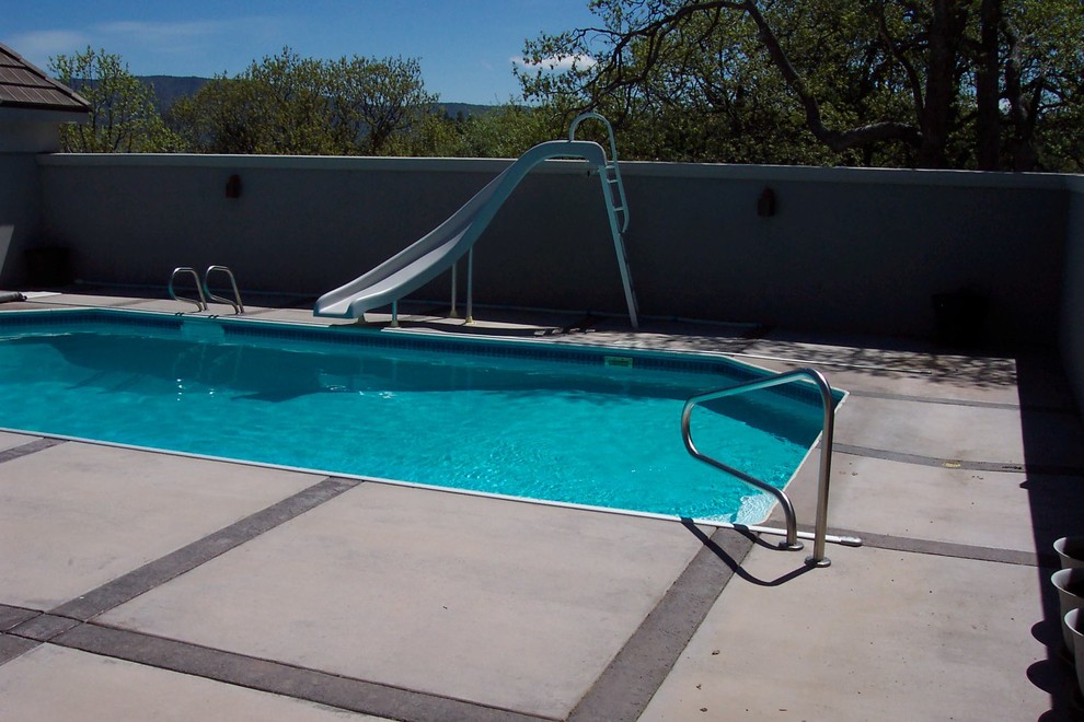Mid-sized traditional backyard rectangular pool in Other with a water slide and natural stone pavers.
