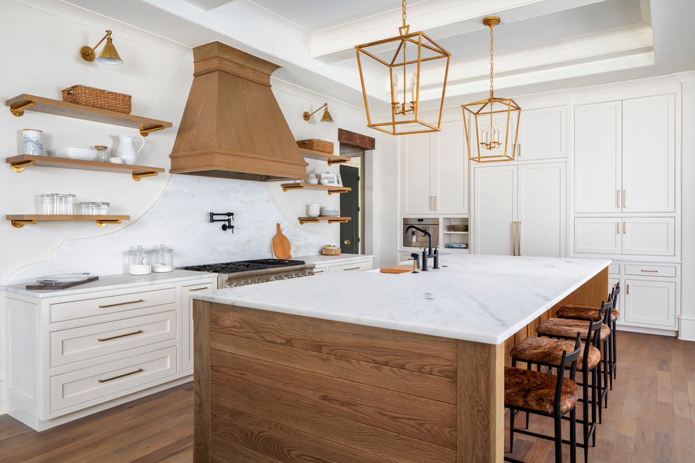 This is an example of an expansive traditional l-shaped eat-in kitchen in Charlotte with a farmhouse sink, marble benchtops, white splashback, stone slab splashback, stainless steel appliances, medium hardwood floors, with island, brown floor and white benchtop.