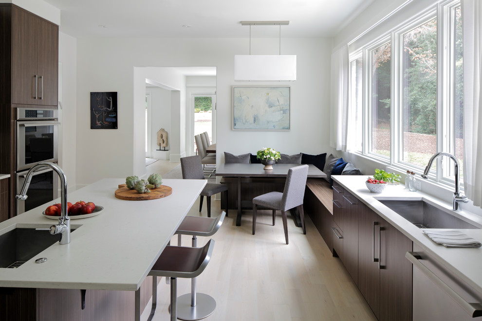 This is an example of a transitional eat-in kitchen in Atlanta with a single-bowl sink, dark wood cabinets, quartz benchtops, white splashback, stainless steel appliances, light hardwood floors and with island.