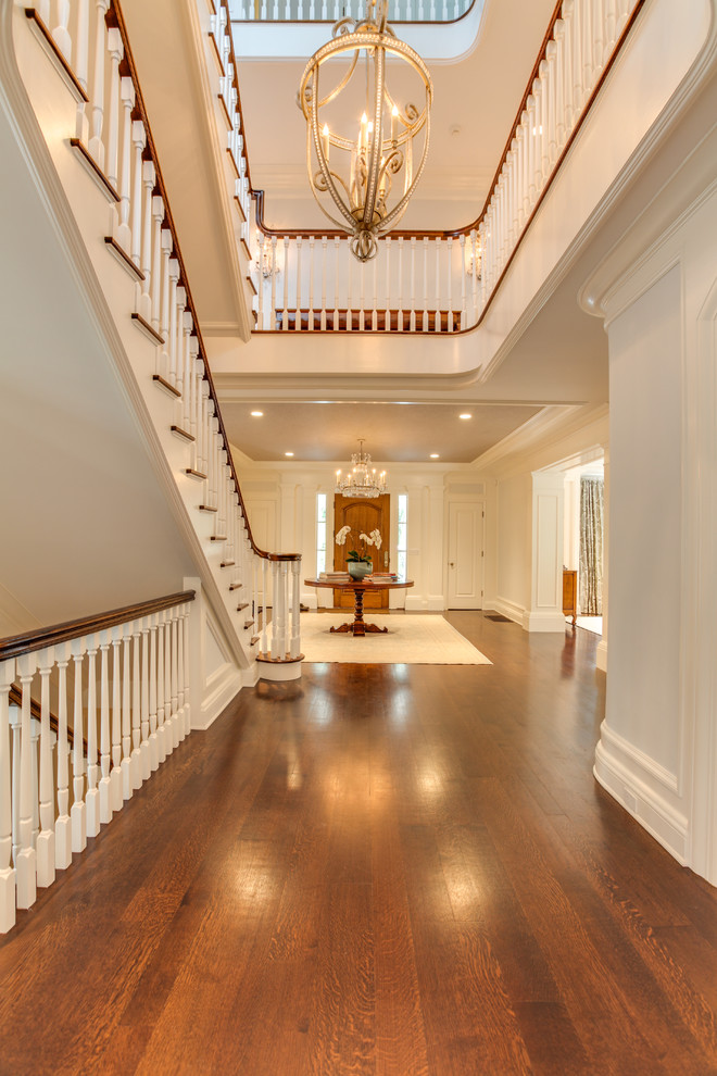 Photo of an expansive traditional foyer in Other with white walls, medium hardwood floors, a single front door, a medium wood front door and brown floor.