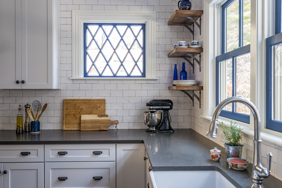 Inspiration for a mid-sized country l-shaped eat-in kitchen in Boston with a farmhouse sink, shaker cabinets, white cabinets, quartz benchtops, white splashback, subway tile splashback, stainless steel appliances, medium hardwood floors and with island.