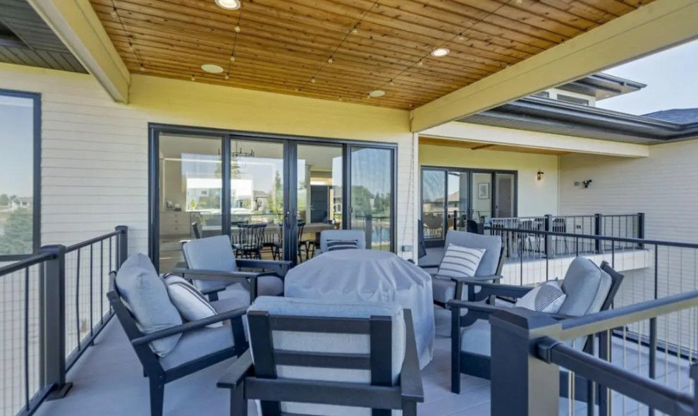 Example of a large transitional backyard second story metal railing deck design with a fire pit and a roof extension
