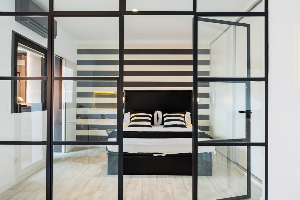 This is an example of a mid-sized contemporary master bedroom in Palma de Mallorca with multi-coloured walls, light hardwood floors and no fireplace.