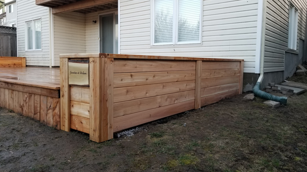 This is an example of a large modern backyard and ground level deck in Ottawa with with skirting, no cover and metal railing.
