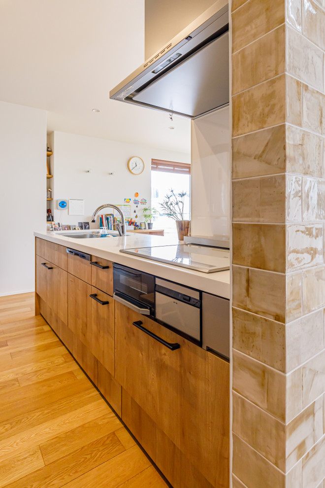 Imagen de cocina lineal de tamaño medio abierta con salpicadero marrón, suelo de madera clara, suelo beige, encimeras blancas y papel pintado
