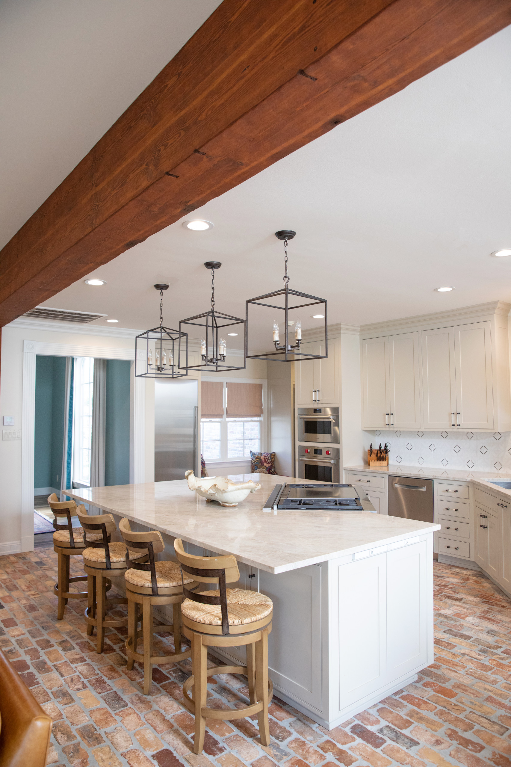 Mid-sized elegant l-shaped brick floor and brown floor open concept kitchen photo in New Orleans with an undermount sink, recessed-panel cabinets, beige cabinets, quartzite countertops, white backspla