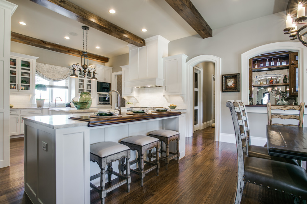 Design ideas for a country u-shaped eat-in kitchen in Dallas with shaker cabinets, white cabinets, white splashback, subway tile splashback, stainless steel appliances, medium hardwood floors and with island.