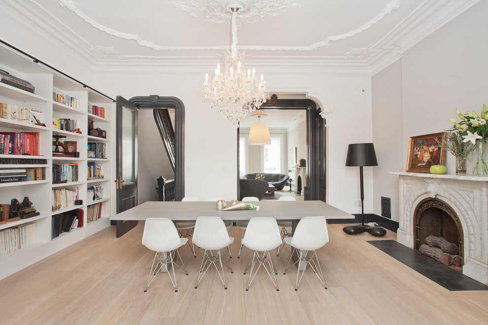 This is an example of a large scandinavian separate dining room in New York with white walls, light hardwood floors, a standard fireplace, a stone fireplace surround and beige floor.