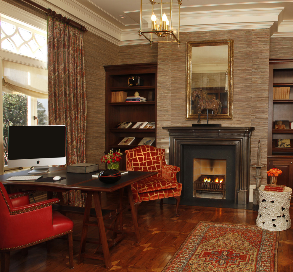 Photo of a traditional home office in San Francisco with brown walls, dark hardwood floors, a standard fireplace and a freestanding desk.