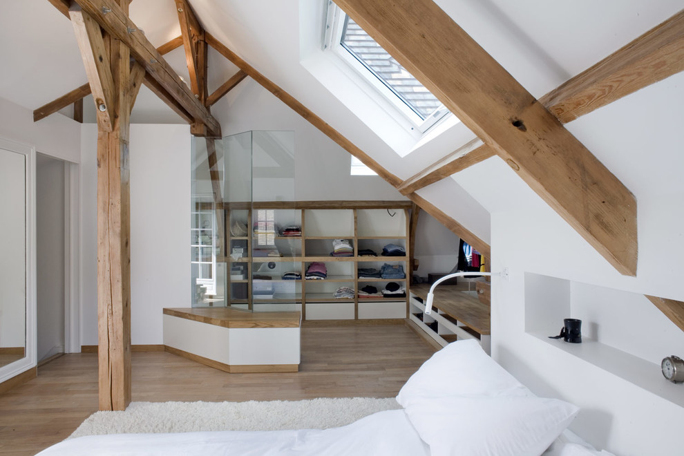 Photo of a country loft-style bedroom in Paris with white walls, medium hardwood floors, brown floor and vaulted.