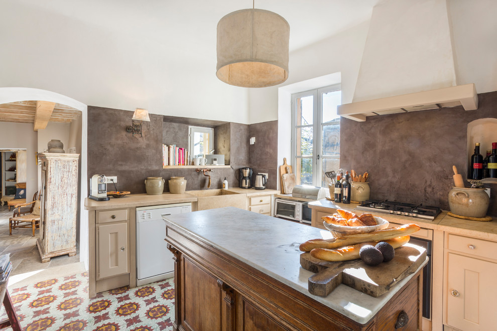 This is an example of a mediterranean l-shaped separate kitchen in Montpellier with a farmhouse sink, beige cabinets, grey splashback, white appliances, with island and multi-coloured floor.