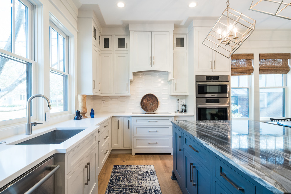 Inspiration for a mid-sized modern u-shaped open plan kitchen in Charleston with an undermount sink, shaker cabinets, white cabinets, quartz benchtops, white splashback, stainless steel appliances, light hardwood floors, with island and brown floor.