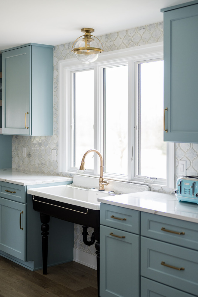 Idee per una cucina design di medie dimensioni con lavello sottopiano, ante in stile shaker, ante blu, top in quarzo composito, elettrodomestici in acciaio inossidabile, pavimento in legno massello medio e top bianco