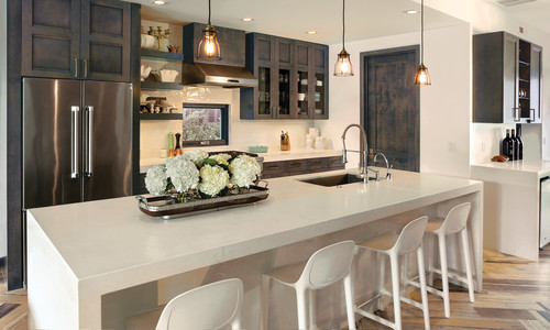 Contemporary kitchen with dark-stained RTA cabinets, glass-front uppers, stainless French-door fridge, floating shelves, and a large quartz waterfall island with sink and bar seating.