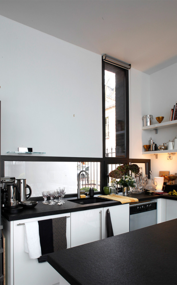 This is an example of a contemporary l-shaped eat-in kitchen in Other with an integrated sink, flat-panel cabinets, white cabinets, window splashback, stainless steel appliances, ceramic floors, with island, black floor, black benchtop and quartzite benchtops.