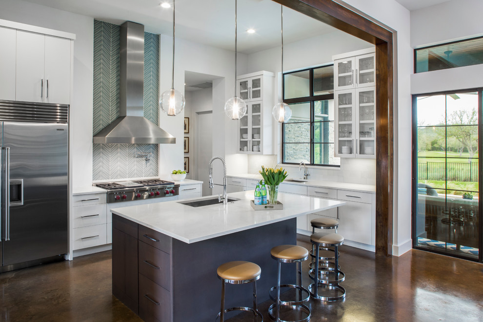Contemporary kitchen in Austin with glass-front cabinets, stainless steel appliances, concrete floors, with island, an undermount sink, white cabinets and multi-coloured splashback.