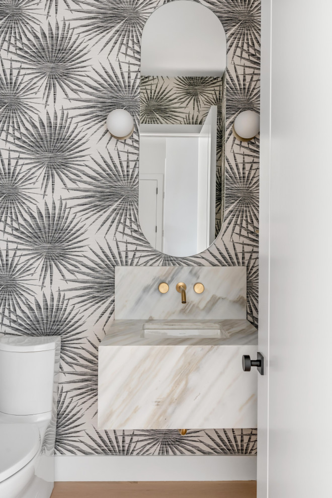 Modern inredning av ett litet flerfärgad flerfärgat toalett, med vita skåp, en toalettstol med hel cisternkåpa, svart och vit kakel, spegel istället för kakel, flerfärgade väggar, ljust trägolv, ett väggmonterat handfat, marmorbänkskiva och brunt golv