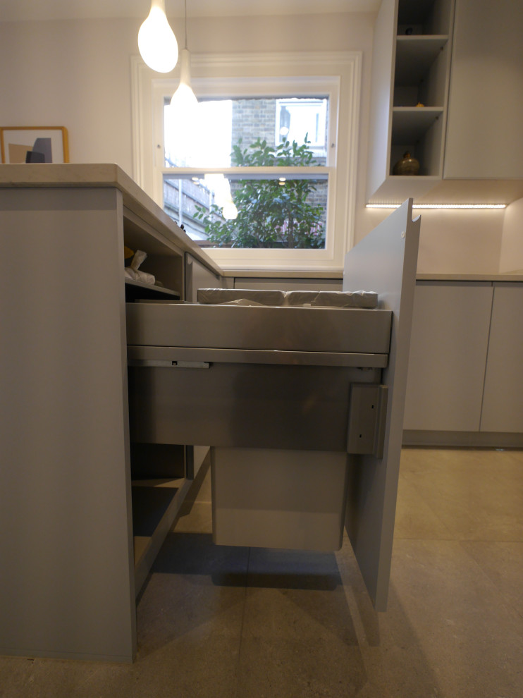 This is an example of a mid-sized contemporary galley separate kitchen in London with an undermount sink, flat-panel cabinets, blue cabinets, quartzite benchtops, white splashback, ceramic splashback, black appliances, ceramic floors, a peninsula, grey floor and white benchtop.