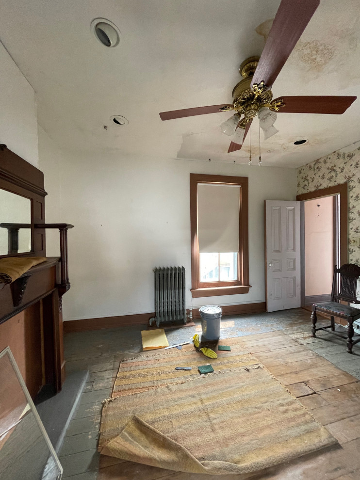 На фото: гостевая спальня среднего размера, (комната для гостей) в викторианском стиле с белыми стенами, светлым паркетным полом, стандартным камином, фасадом камина из дерева, коричневым полом и обоями на стенах с