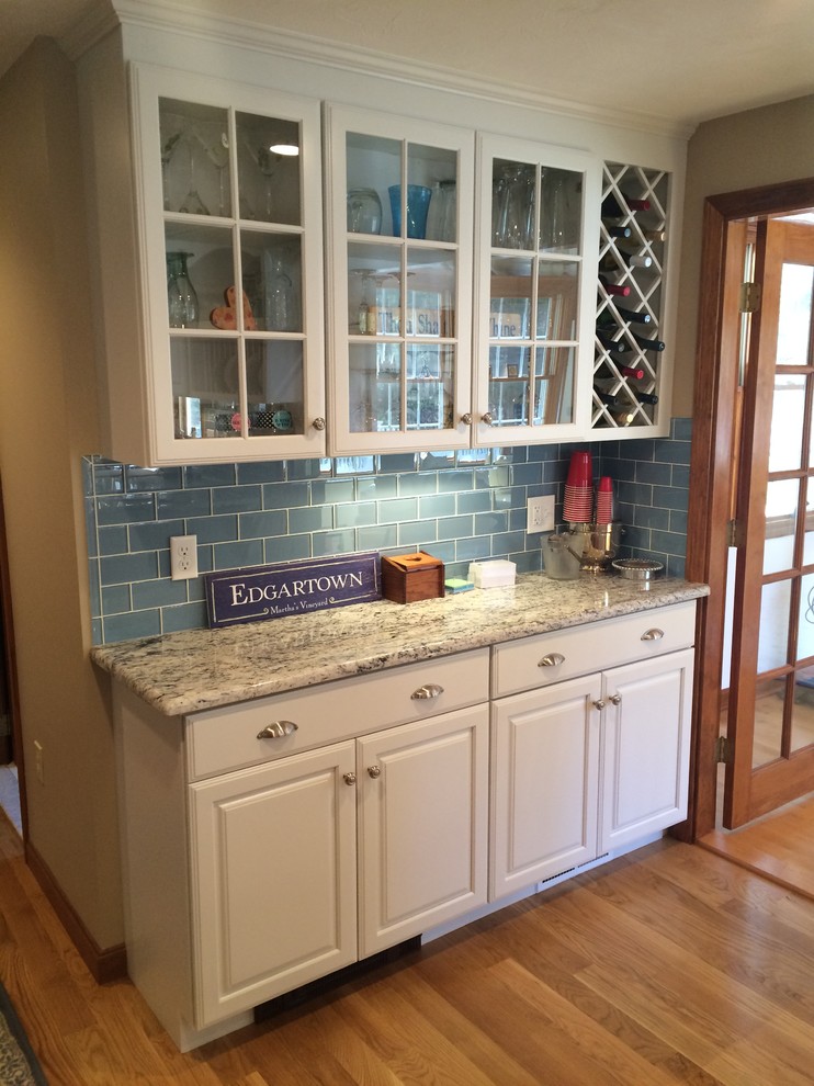 Transitional u-shaped medium tone wood floor eat-in kitchen photo in Boston with an undermount sink, raised-panel cabinets, white cabinets, granite countertops, blue backsplash, glass tile backsplash, stainless steel appliances and an island