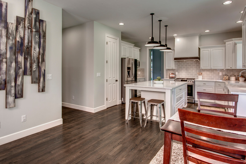 Example of a large transitional u-shaped dark wood floor and brown floor eat-in kitchen design in Seattle with an undermount sink, raised-panel cabinets, white cabinets, marble countertops, gray backsplash, ceramic backsplash, stainless steel appliances and an island