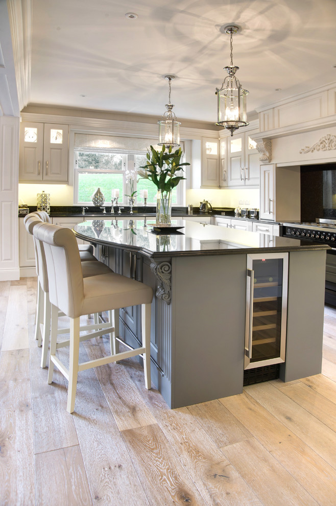 Design ideas for a large traditional u-shaped eat-in kitchen in Other with an integrated sink, raised-panel cabinets, white cabinets, granite benchtops, black splashback, stainless steel appliances, medium hardwood floors, with island, brown floor and black benchtop.