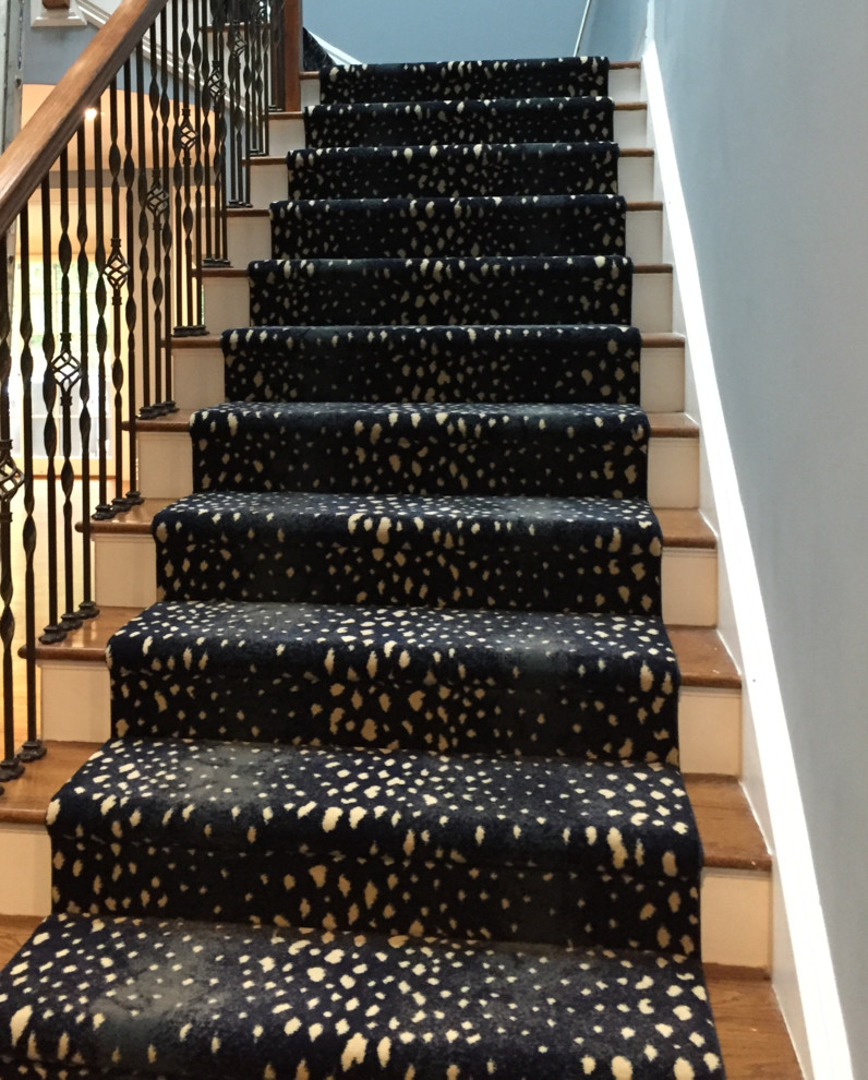 Photo of a large midcentury carpeted l-shaped staircase in New York with carpet risers and wood railing.