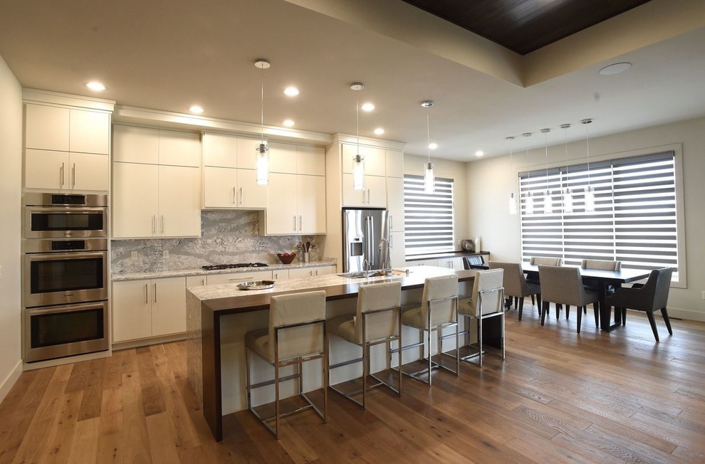 Design ideas for an eat-in kitchen in Other with an undermount sink, flat-panel cabinets, white cabinets, quartz benchtops, stainless steel appliances, light hardwood floors and with island.