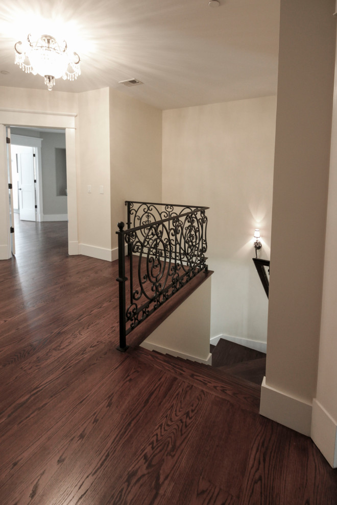 Expansive transitional wood curved staircase in DC Metro with wood risers and metal railing.