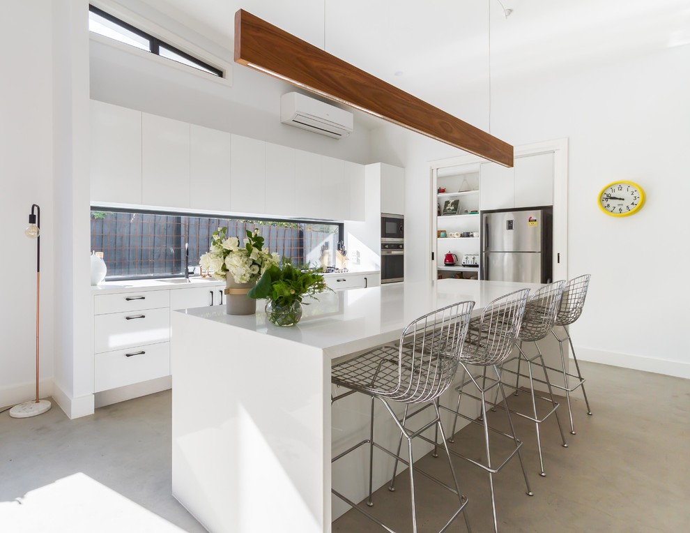 Inspiration for a large modern galley open plan kitchen in Melbourne with a double-bowl sink, flat-panel cabinets, white cabinets, quartz benchtops, window splashback, stainless steel appliances, concrete floors and with island.