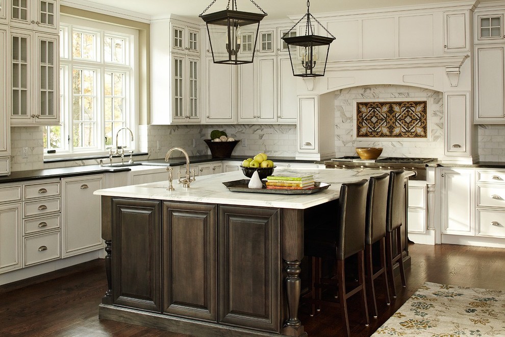 Inspiration for a large traditional u-shaped eat-in kitchen in New York with raised-panel cabinets, white cabinets, marble benchtops, white splashback, subway tile splashback, dark hardwood floors, with island, a farmhouse sink and panelled appliances.