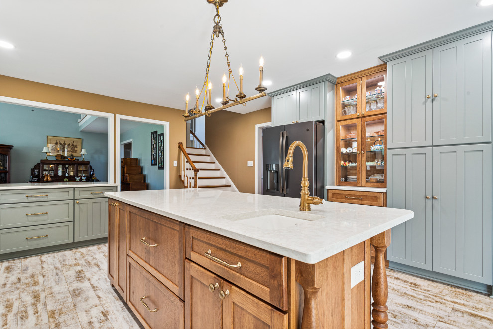 Inspiration for an expansive u-shaped kitchen/diner in DC Metro with a belfast sink, recessed-panel cabinets, turquoise cabinets, engineered stone countertops, brick splashback, black appliances, light hardwood flooring, an island and white worktops.