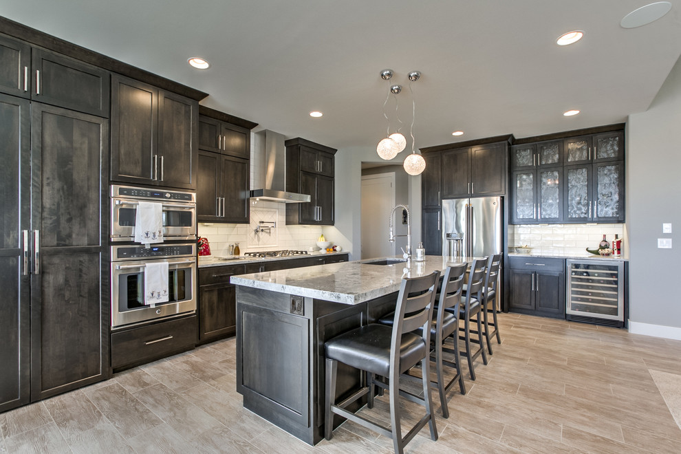 This is an example of a transitional open plan kitchen in Omaha with an undermount sink, shaker cabinets, dark wood cabinets, granite benchtops, white splashback, mosaic tile splashback, stainless steel appliances, porcelain floors and with island.