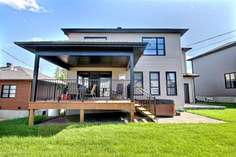 Photo of a mid-sized contemporary two-storey grey exterior in Montreal with mixed siding and a hip roof.