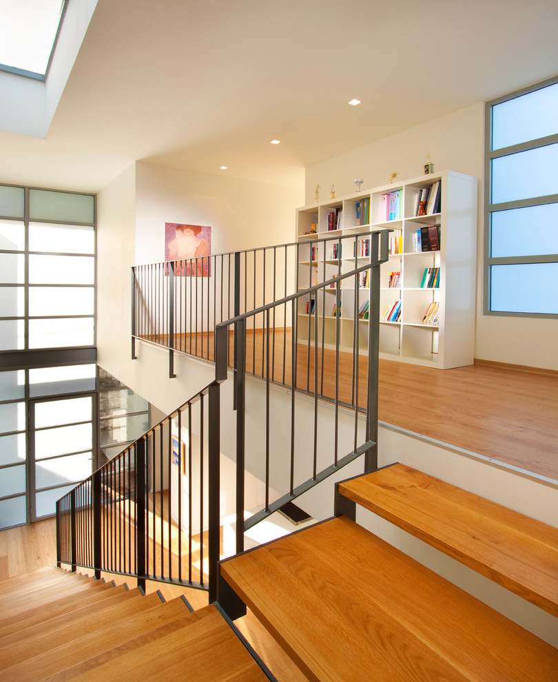 Photo of a contemporary wood staircase in Other with open risers and metal railing.