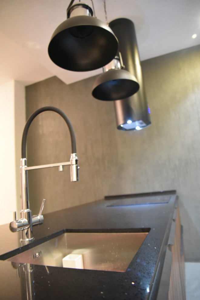 Idee per una cucina minimal di medie dimensioni con lavello sottopiano, ante lisce, ante nere, top in superficie solida, elettrodomestici neri, pavimento in gres porcellanato, pavimento multicolore e top nero