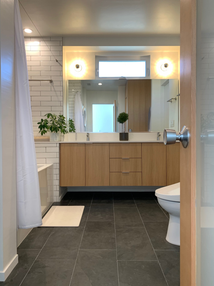 Small transitional master bathroom in Los Angeles with flat-panel cabinets, light wood cabinets, an alcove tub, a shower/bathtub combo, a bidet, white tile, cement tile, white walls, slate floors, an undermount sink, quartzite benchtops, black floor, a shower curtain and white benchtops.