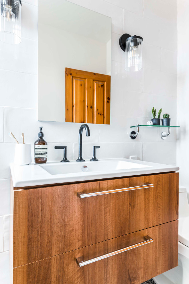 This is an example of a small eclectic 3/4 bathroom in Montreal with flat-panel cabinets, medium wood cabinets, an open shower, white tile, ceramic tile, porcelain floors, an integrated sink, black floor, an open shower, white benchtops, white walls and engineered quartz benchtops.