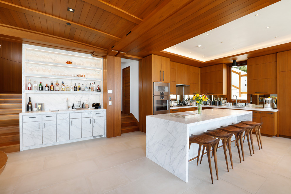 Design ideas for a large modern l-shaped open plan kitchen in Orange County with an undermount sink, flat-panel cabinets, medium wood cabinets, mirror splashback, stainless steel appliances, with island, beige floor, white benchtop and marble benchtops.