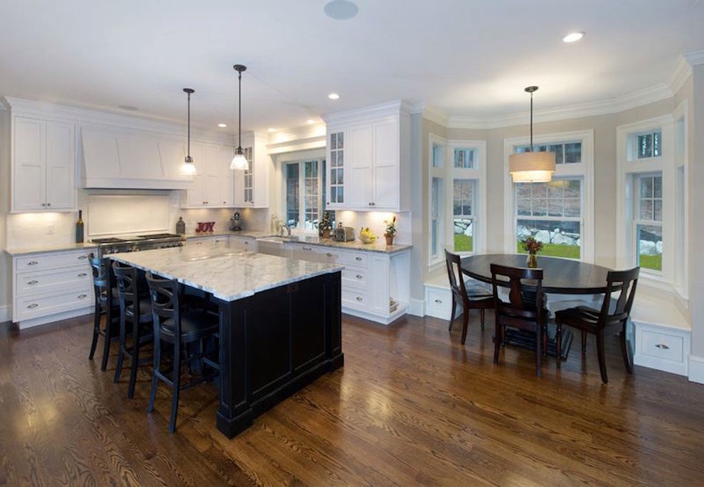 Example of a transitional medium tone wood floor open concept kitchen design in Boston with shaker cabinets, white cabinets, marble countertops and an island