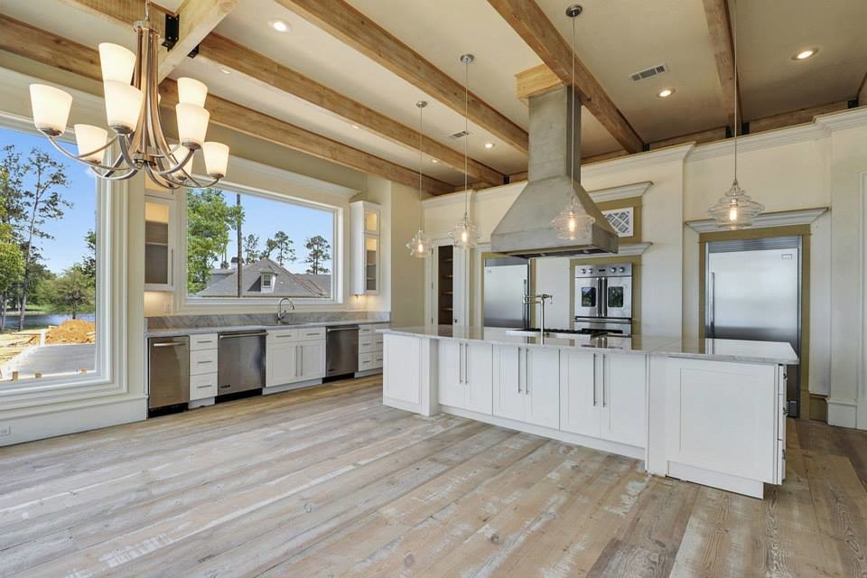 Design ideas for a large traditional galley open plan kitchen in New Orleans with an undermount sink, recessed-panel cabinets, white cabinets, granite benchtops, stainless steel appliances, medium hardwood floors, with island and brown floor.