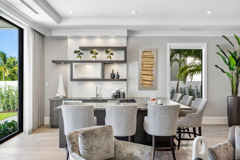 Contemporary seated home bar in Miami with an undermount sink, dark wood cabinets, marble benchtops, medium hardwood floors, brown floor and black benchtop.
