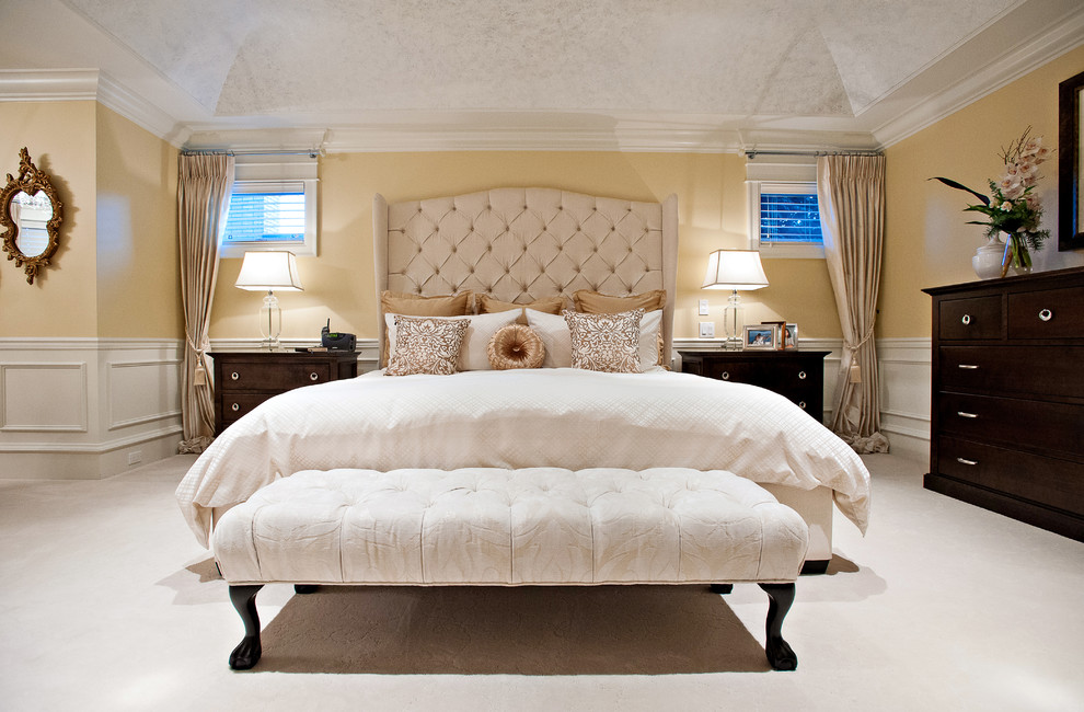 This is an example of a large traditional master bedroom in Vancouver with yellow walls, carpet and white floor.